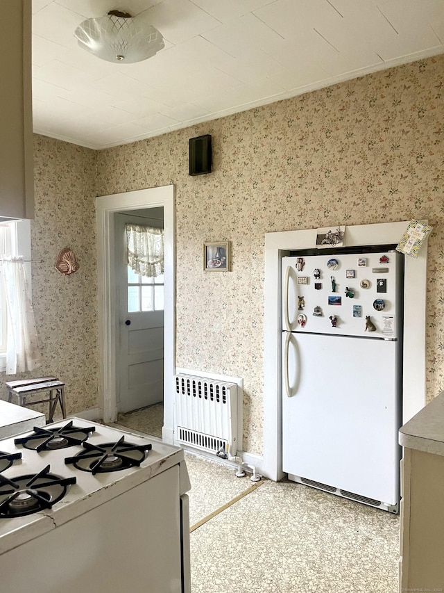 kitchen with wallpapered walls, radiator heating unit, and white appliances
