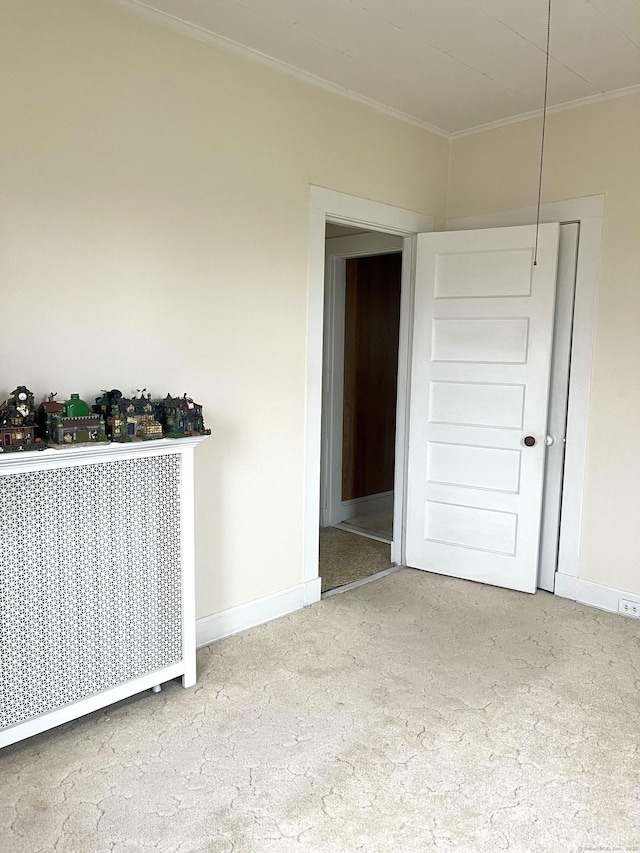 empty room with crown molding, radiator heating unit, baseboards, and carpet floors