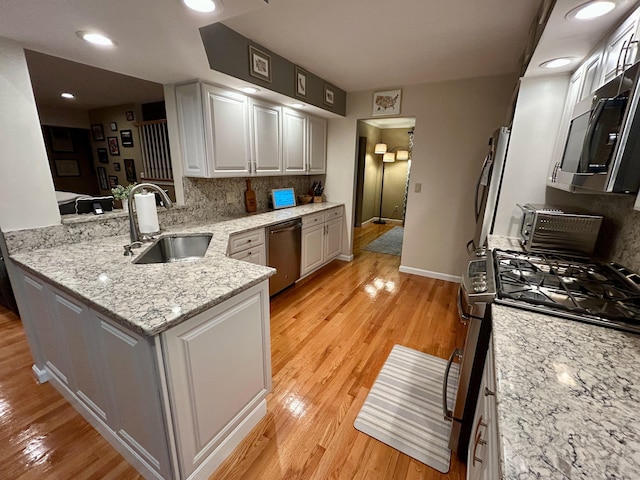 92 Sherwood Ln, Norwich, CT 06360 - kitchen featuring appliances with stainless steel finishes, a sink, decorative backsplash, a peninsula, and light wood-style floors