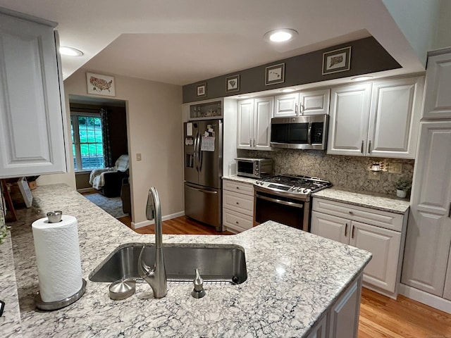 92 Sherwood Ln, Norwich, CT 06360 - kitchen with appliances with stainless steel finishes, a sink, decorative backsplash, light wood-type flooring, and light stone countertops