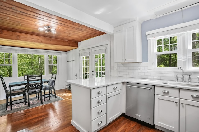 12 Woody Pl, Ridgefield, CT 06877 - kitchen featuring dishwasher, a sink, a peninsula, backsplash, and white cabinetry