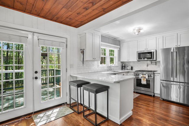 12 Woody Pl, Ridgefield, CT 06877 - kitchen with appliances with stainless steel finishes, a peninsula, backsplash, a sink, and white cabinetry