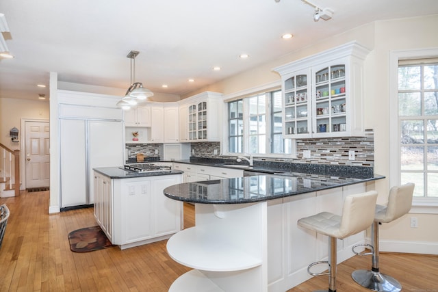 7 Brighton Ln, Simsbury, CT 06070 - kitchen featuring a peninsula, a center island, glass insert cabinets, paneled refrigerator, and tasteful backsplash