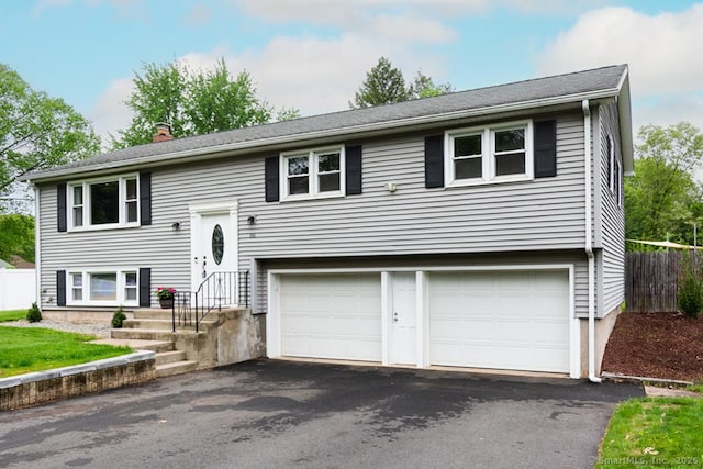 86 Rustic Ln, East Hartford, CT 06118 - split foyer home featuring asphalt driveway, a chimney, a garage, and fence