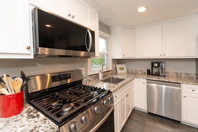 86 Rustic Ln, East Hartford, CT 06118 - kitchen featuring appliances with stainless steel finishes, a sink, white cabinets, dark tile patterned flooring, and light stone counters