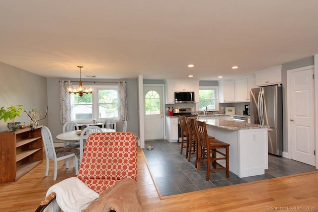 86 Rustic Ln, East Hartford, CT 06118 - kitchen featuring stainless steel appliances, a chandelier, white cabinetry, a center island, and light stone countertops