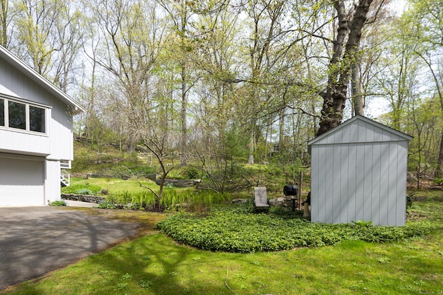 102 Colonial Rd, Guilford, CT 06437 - view of yard featuring asphalt driveway, a garage, and a shed