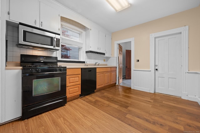 175 Lincoln St, Middletown, CT 06457 - kitchen featuring black appliances, light wood-style flooring, light countertops, backsplash, and a wainscoted wall