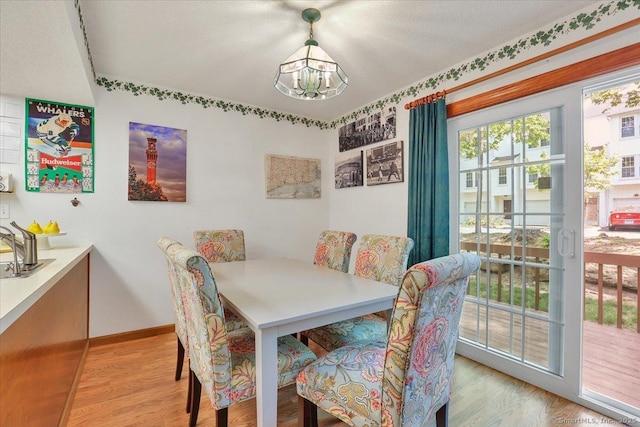dining area with a chandelier, light wood finished floors, and baseboards