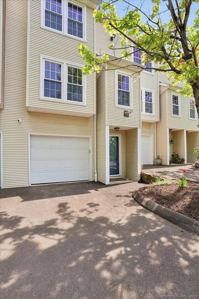 view of property with asphalt driveway and an attached garage