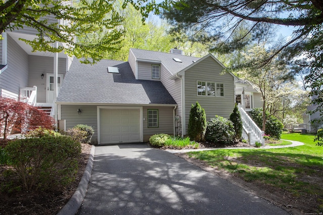view of front facade featuring a chimney, driveway, a garage, stairs, and roof with shingles