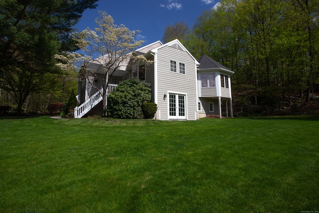 rear view of house with a yard, a sunroom, and french doors