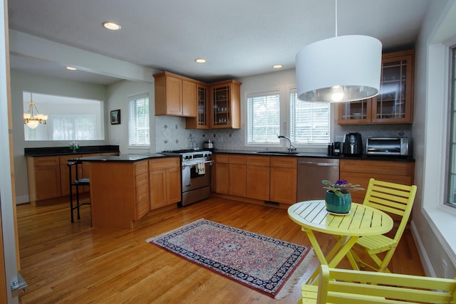 kitchen with stainless steel appliances, decorative backsplash, light wood-type flooring, and a healthy amount of sunlight