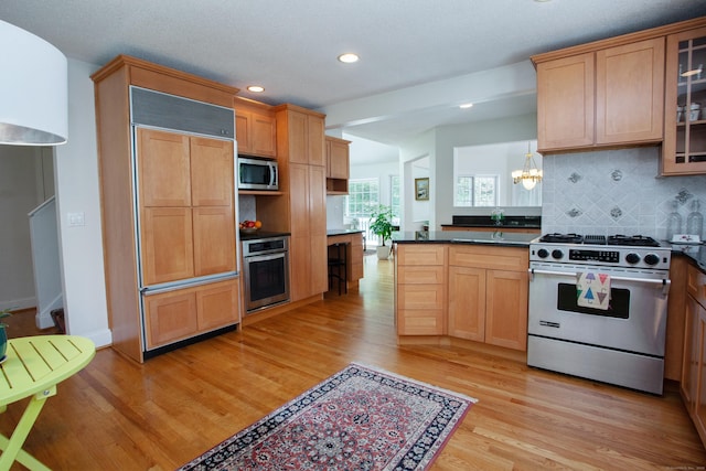 kitchen with stainless steel appliances, recessed lighting, light wood-style flooring, decorative backsplash, and dark countertops