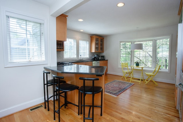 kitchen with a healthy amount of sunlight, a peninsula, visible vents, and a kitchen bar