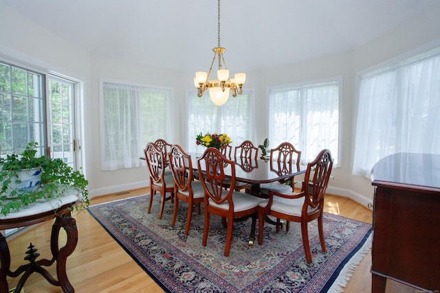 dining area featuring an inviting chandelier, light wood-type flooring, and baseboards
