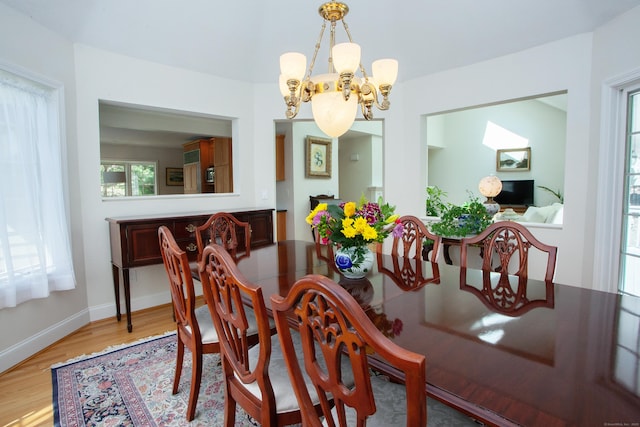 dining room with baseboards, an inviting chandelier, and light wood-type flooring
