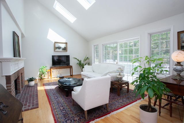 living room featuring a skylight, a brick fireplace, high vaulted ceiling, and wood finished floors