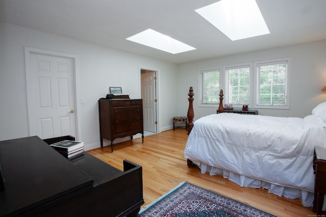 bedroom with a skylight, baseboards, and light wood-style floors