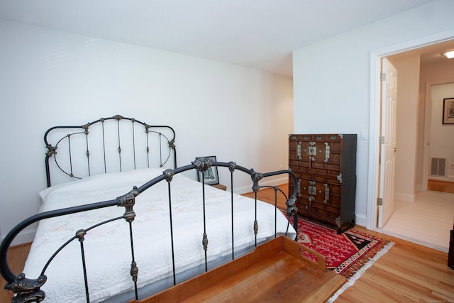 bedroom with baseboards, visible vents, and wood finished floors