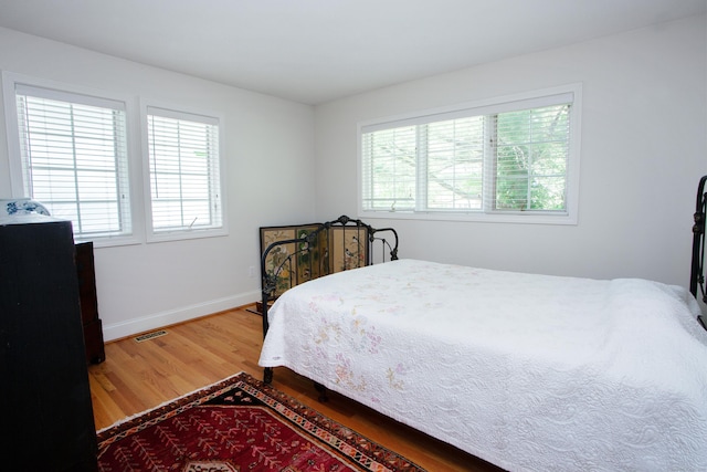 bedroom featuring visible vents, wood finished floors, and baseboards