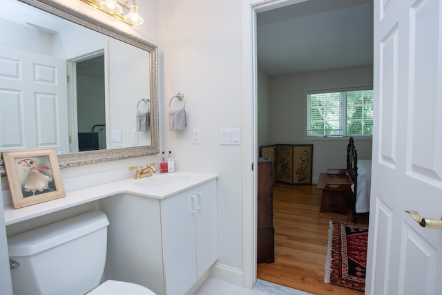 half bathroom featuring vanity, toilet, and wood finished floors