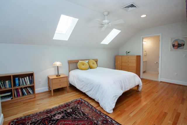 bedroom featuring vaulted ceiling with skylight, baseboards, visible vents, and wood finished floors