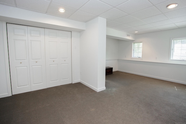 basement featuring baseboards, carpet flooring, a paneled ceiling, and visible vents