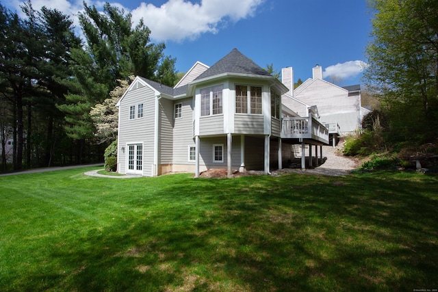back of property featuring a lawn, a wooden deck, and french doors