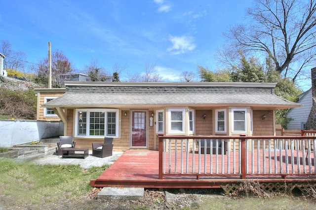rear view of property featuring roof with shingles and a wooden deck
