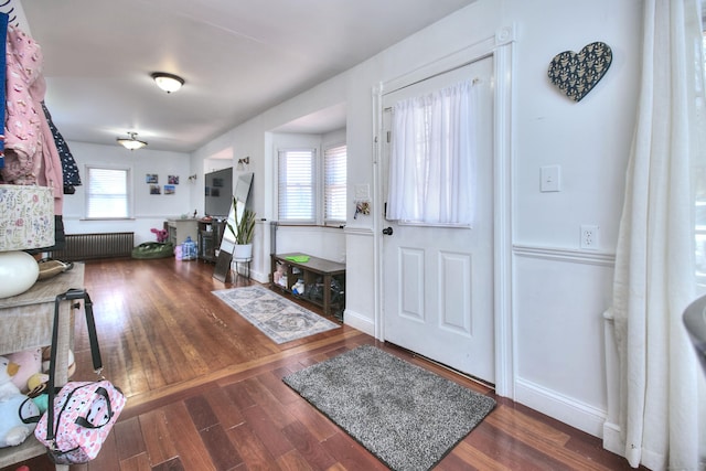 foyer entrance featuring radiator, wood finished floors, and baseboards