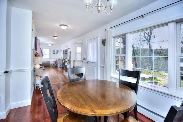dining area with a chandelier, baseboard heating, wood finished floors, and baseboards