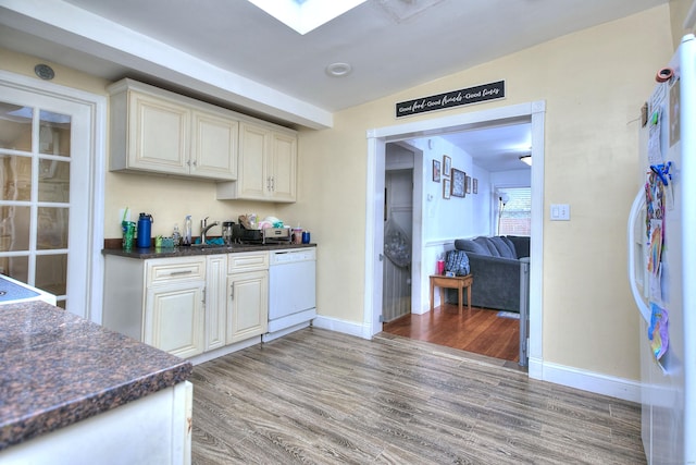 kitchen with white dishwasher, light wood finished floors, baseboards, and a sink