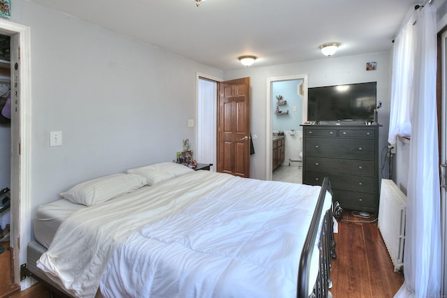 bedroom featuring radiator, wood finished floors, and ensuite bathroom