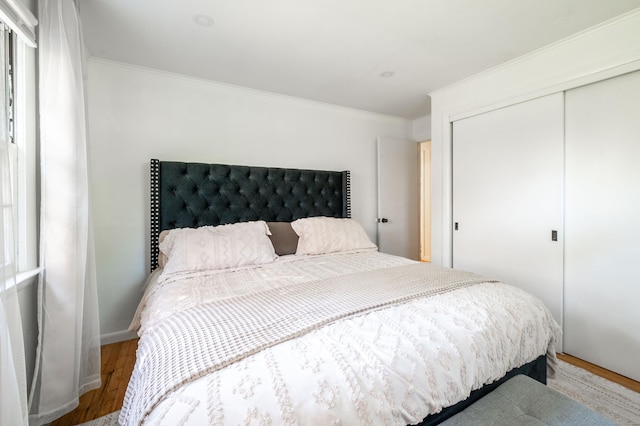 bedroom featuring wood finished floors, a closet, and crown molding
