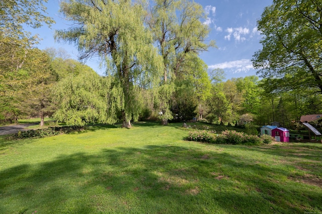 view of green lawn with a storage unit and an outbuilding