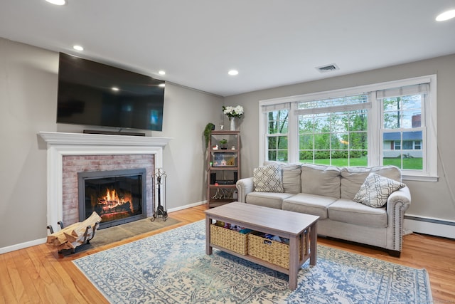 living room with a wealth of natural light, baseboard heating, visible vents, and wood finished floors