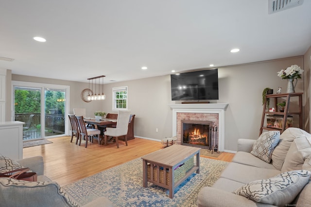 living room with visible vents, light wood-style flooring, a fireplace, and recessed lighting