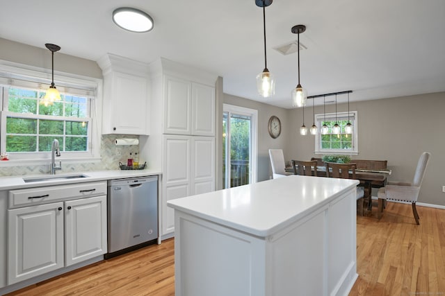 kitchen with stainless steel dishwasher, a sink, white cabinetry, light countertops, and light wood-type flooring