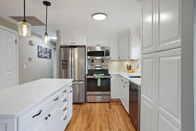kitchen featuring stainless steel appliances, backsplash, light countertops, and light wood-type flooring
