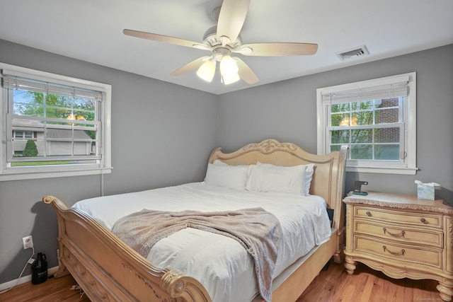 bedroom featuring multiple windows, visible vents, wood finished floors, and a ceiling fan
