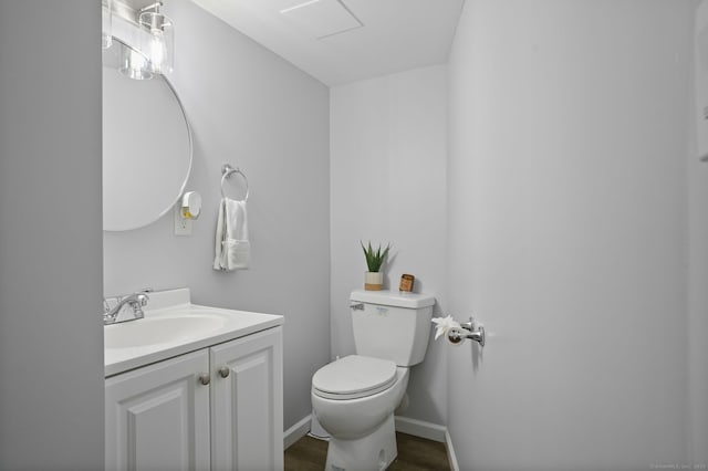 bathroom with toilet, baseboards, vanity, and wood finished floors