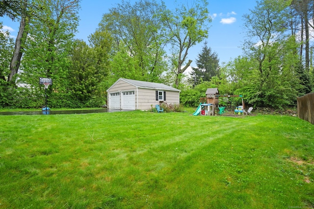 view of yard with fence, an outbuilding, a playground, and a detached garage