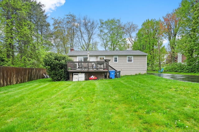 back of property featuring a yard, a chimney, a wooden deck, and fence