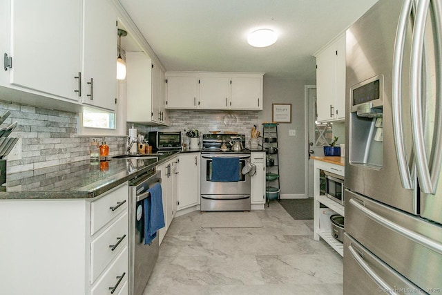 kitchen featuring appliances with stainless steel finishes, backsplash, white cabinets, dark countertops, and a sink