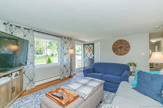 living room with a baseboard heating unit and light wood-style flooring