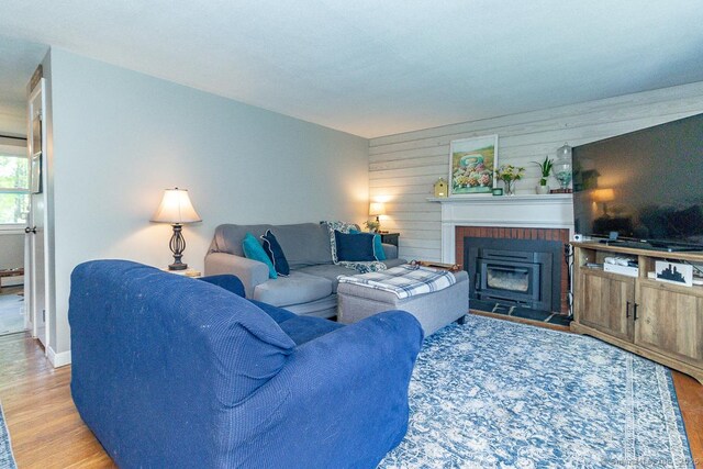 living room featuring wood finished floors, a fireplace, wood walls, and baseboards