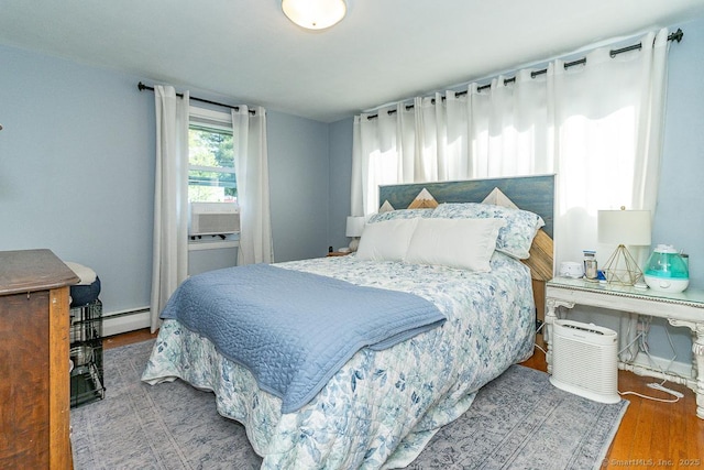 bedroom featuring wood finished floors and a baseboard heating unit