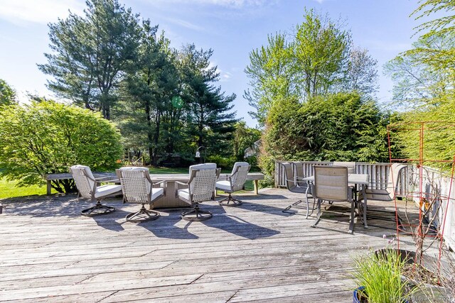 wooden deck with outdoor dining space and view of wooded area
