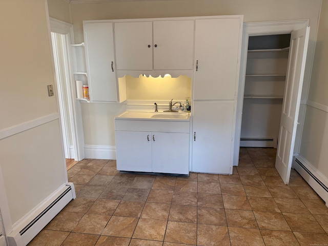 kitchen with a baseboard heating unit, white cabinets, and a sink